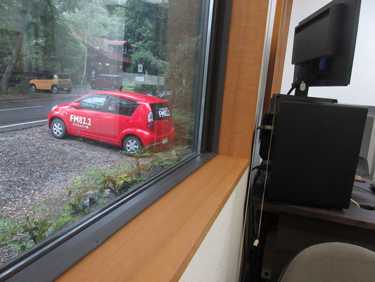 窓外を見ると、これまたかわいい82.2と記されたFM八ヶ岳の赤い車　この日は建物内隣接するスペースで他の収録もしていた