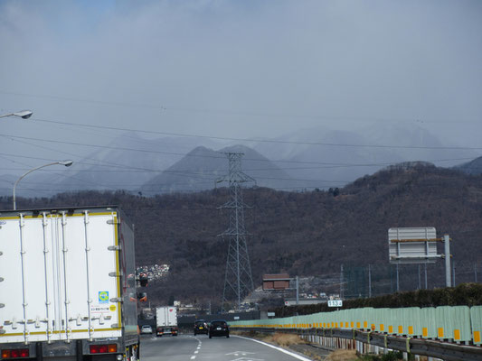 霞んだ鼻曲山の手前の黒っぽい双耳峰のように見えるのは、太刀岡山（たちおかやま）だった　普段は気づかないが、吹雪のベールで手前の山の存在感が増した