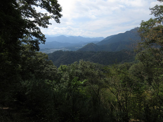 稜線の向こうでは飛び立ったパラグライダーが優雅に浮かんでいた　向こうの山並みは倉岳山方面