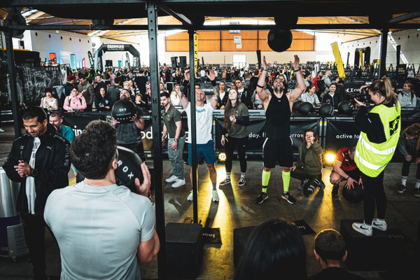 Hyrox Wall Balls Station im Wettkampf – Athleten in vollbesetzter Messehalle 2023