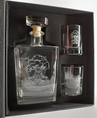 Whiskeyfles met glazen met logo gegraveerd en tekst.