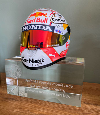 De helm van Max Verstappen op een glazen standaard met gravure.