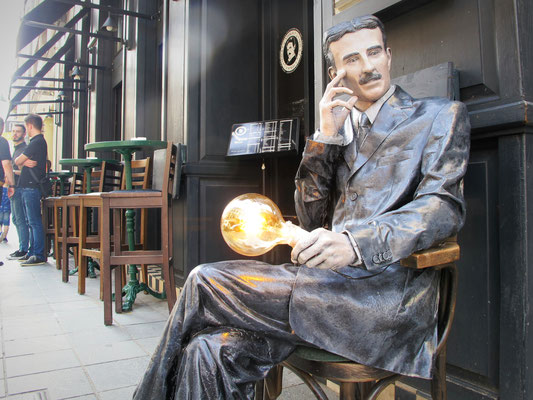 Nikola Tesla, Sohn der Stadt, sitzt mit Lampe vor dem Café, das seinen Namen trägt.