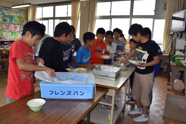 教室で給食を配膳する5年生