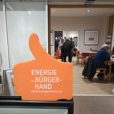 Schaumstoffhand mit dem Text "Energie-Bürgerhand" mit dem Blick in den Sall