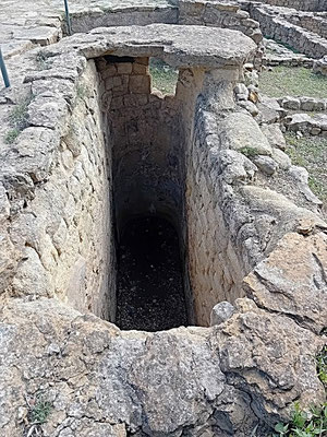 Zisterne in Ullastret. Eine der Bedeckungsplatten ist noch zu sehen. Hinten ein Auslauf- oder Einlaufloch