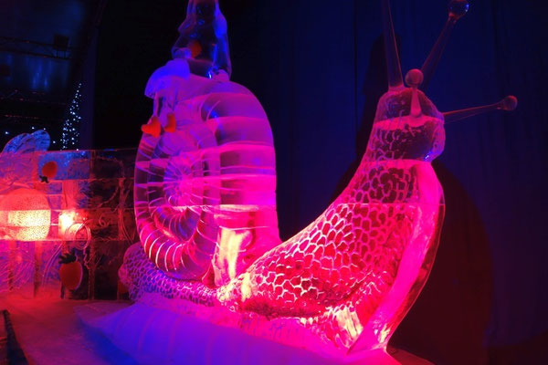 Eine riesige, beleuchtete Eisskulptur in Form einer kunstvollen Schnecke.