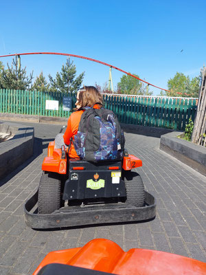 Gelaunt in einem kleinen orangefarbenen Elektroauto auf der Kartbahn
