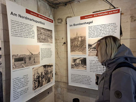 Historische Informationstafeln an der rauen Betonwand im Inneren des Bunkers