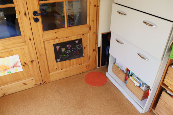 Viona als Kind liegt in der Ecke der Durchgangstür / Aktenschrank und schaut auch in die selbige Ecke