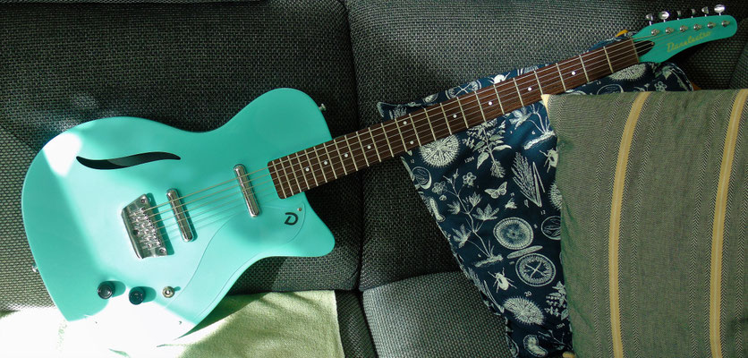 Die erste halbakustische: Danelectro 56 Vintage Baritone Dark Aqua ("die Blaue"). Das transparente Schlagbrett fällt optisch kaum auf. Das stilisierte f-Loch verrät den teilweise ausgehöhlten Korpus.  Charakteristisch: die "Lippenstift"-pickups.