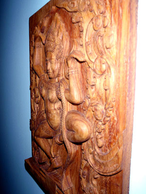 Holzrelief im Profil: eine Tänzerin umgeben von floralen Mustern