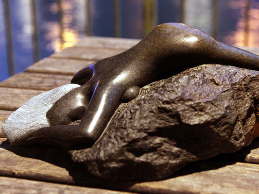Serpentin-Skulptur: eine nackte Frau liegt bauchlings auf einem Stein