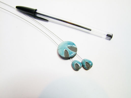Collier de créateur en poterie posé à côté d'un stylo noir
