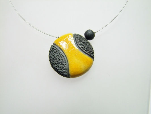Pendentif en perle de céramique noire et jaune avec effet de texture pierre de lave vue en gros plan