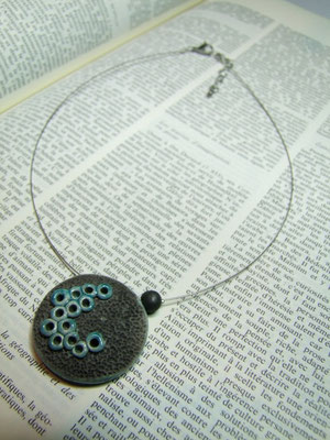 collier noir et bleu posé sur une page de livre