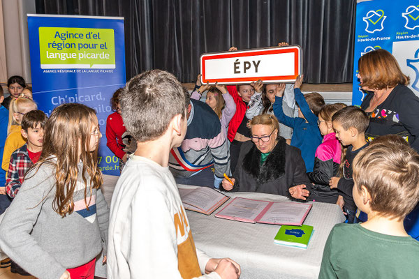 Les enfants sont heureux d'entourer la table et de porter la pancarte
