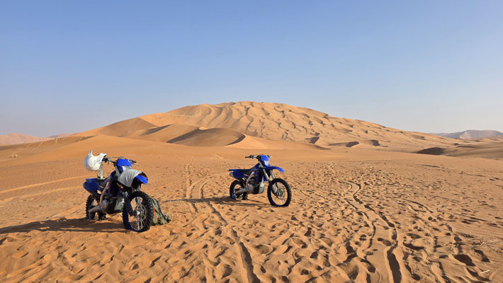 ZWEI ENDUROMOTORRÄDER IN DER SANDWÜSTE VOR EINER DÜNE