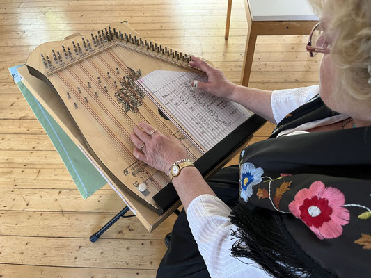 Helga Spörhase demonstriert, wie man eine Akkordzither mit den Unterlegnoten spielt. Foto: Herma Niemann