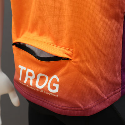 Custom branded short sleeve MTB jersey close-up showing rear pocket construction and printed fabric.