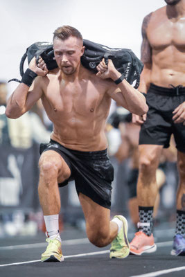 Christoph Wieloch mit Sandbag auf den Schultern bei den Ausfallschritten (Sandbag Lunges) im HYROX Frankfurt Race.