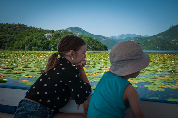 Zwei Kinder beobachten still den Skadarsee vom Boot aus