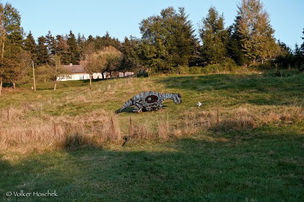 T-Rex steht auf einer Wiese auf dem Bogenparcours Dinosaurier-Park.