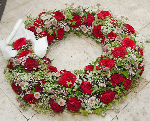 Rundgesteckter Kranz mit roten Rosen Wiesenblumen