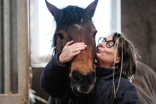 femme qui tient la tête de son cheval et l'embrasse