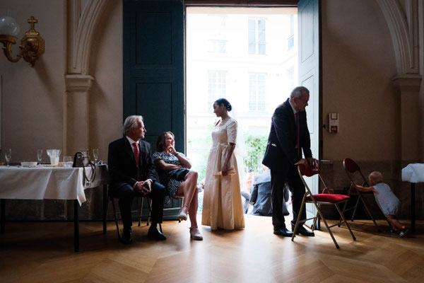 marié en contre jour dans l'encadrement d'une grande porte parle à des amis