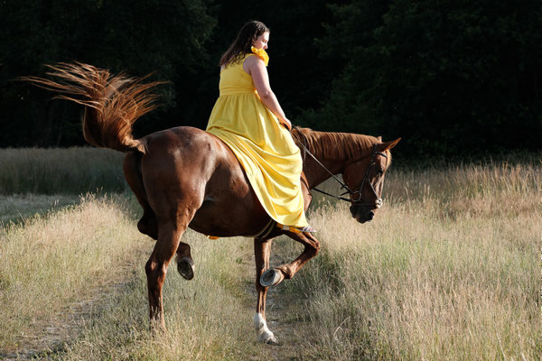 Femme en robe jaune sur son cheval qui piaffe