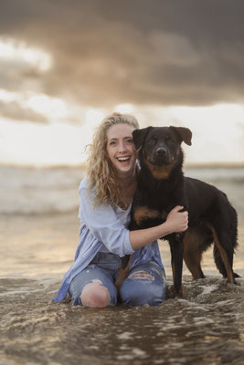Frau, lachend, mit schwarzem Hund Fotoshooting am Meer, Julianadorp
