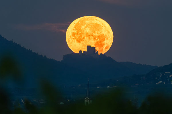 Weit entfernter Vollmonduntergang hinter dem Trifels