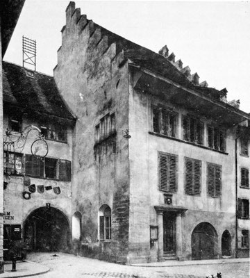 Das Rathaus um 1910, als im Erdgeschoss noch kein Geschäftslokal eingebaut war. Gegen die Grosse Kirchgasse hin sieht man drei Eingänge. Markant das sehr hohe Tor links, flankiert von zwei Säulen, oben der Wappenstein.