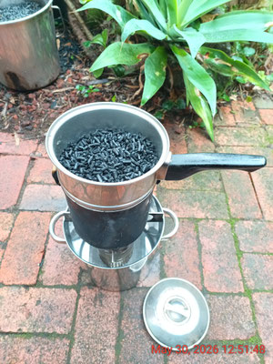 A '2 in 1' steamer and water filter sitting on top of a 3L billy - in 'Filter mode' - for pre-pasteurization water treatment using biochar pellets from a previous stove burn
