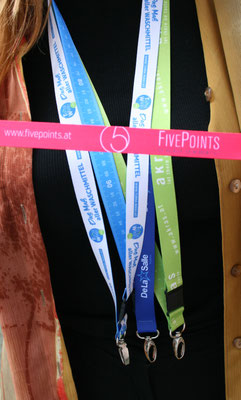 Eine Dame trägt drei Lanyards um ihren Hals. Quer vor ihr präsentiert sie das Lanyard von Five Points Promotion.