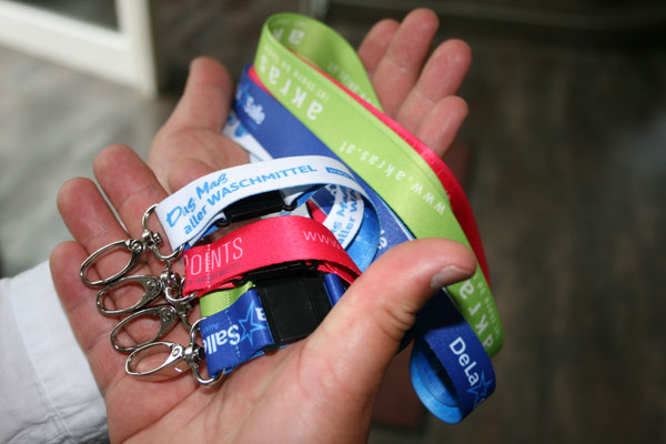 Aus einer Hand hängen mehrere Lanyards, die allesamt mit einem Wire-O-Karabiner ausgestattet sind.