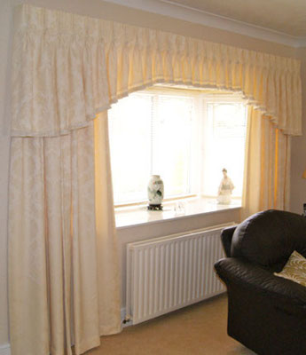 A shaped triple pinch pleat trimmed valance with floor length curtains