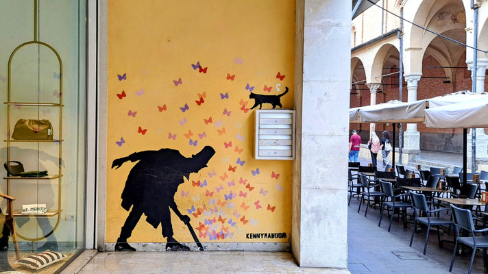Streetart: Schwarze Figur mit Zylinder, Katze und Schmetterlingen