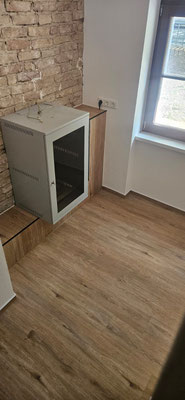 Altbau modernisiert mit Vinylboden in Laminatoptik, Backstein-Sichtmauerwerk und harmonisch gestaltetem Sockel aus Vinyl.