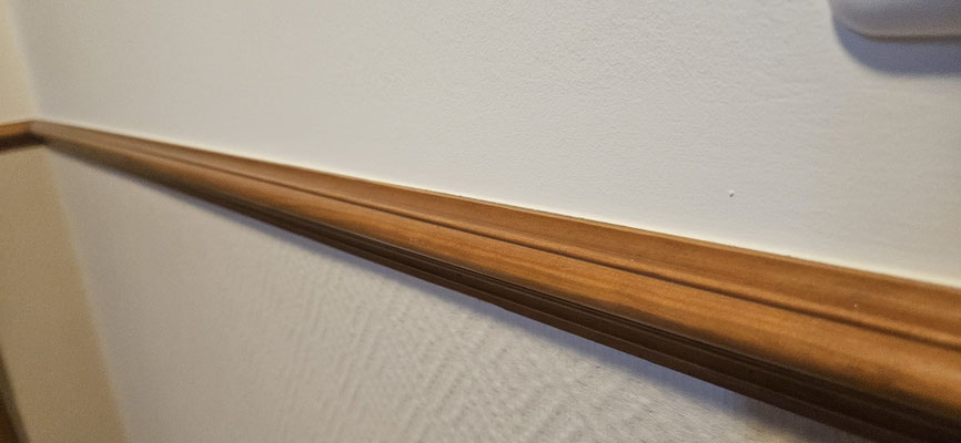 Altbau-Treppenhaus nach Sanierung mit lasiertem Geländer, zweigeteilter Wandgestaltung durch Holzsockel