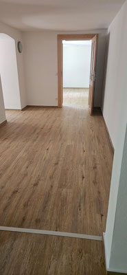Altbau kombiniert Tradition und Moderne: Laminat-Optik-Vinylboden, rustikale Backsteinwand