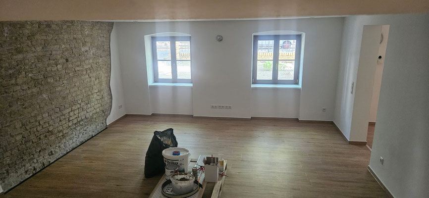 Altbaurenovierung mit Vinylboden in Laminatoptik und freigelegtem Sichtmauerwerk für rustikalen Charme.