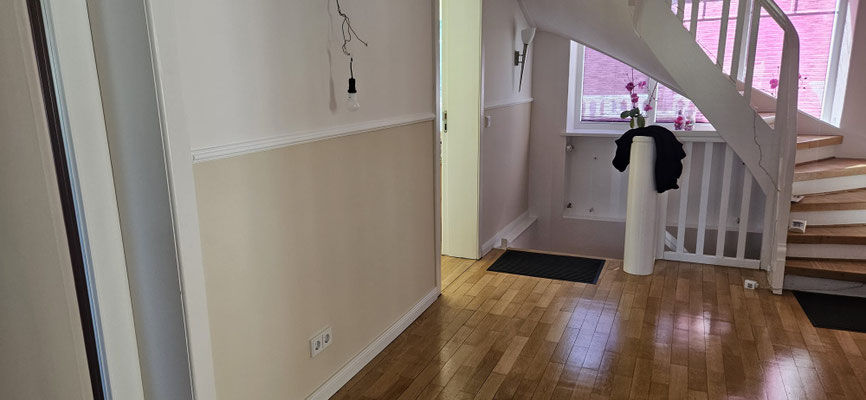 Wandgestaltung in Beige und Creme, weißer Stuckleiste und warmem Parkettboden.