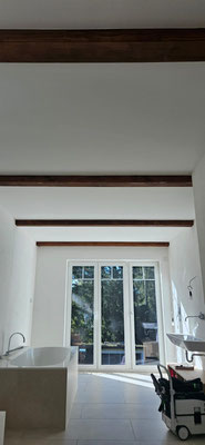 Helles, renoviertes Badezimmer mit weißen Wänden und integrierten Echtholzbalken, die natürliche Wärme ins moderne Design bringen.