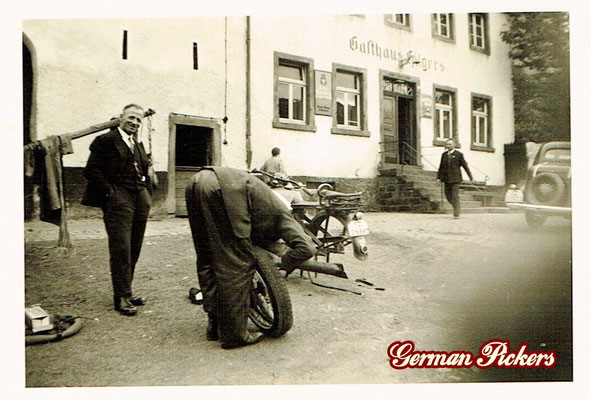 AK / Foto Herren reparieren Motorrad - Im Hintergrung ein Hinterglasschild Nette Bräu Wirtshaus