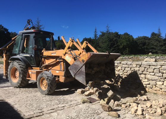 Approvisionnement en pierres de complément avec le tracto-pelle...