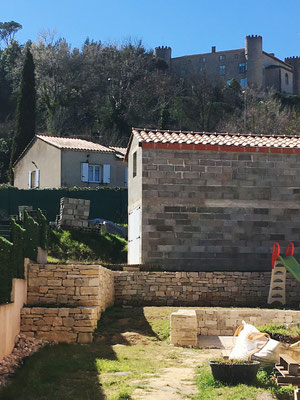 Vue d'ensemble depuis le chemin du Grand Logis. En premier plan à gauche, le mur en pierre sèche et à droite, le muret en parement  de pierres naturelles. Tout au fond, se dresse le château de Mirabeau.