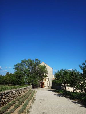 Vue d'ensemble du portail d'entrée et du parvis de l'église N.D. de Ganagobie, qui se trouve à quelques centaines de mètres du mur de clôture. Le ciel, d'un bleu fluide et saturé, est caractéristique de celui du Luberon