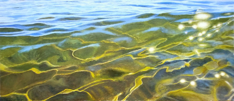 Reflejos de luz sobre agua marina transparente con tonos verdes y azules.